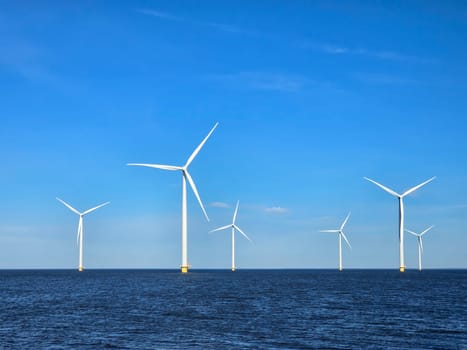 Windmill park in the ocean, view of windmill turbines generating green energy electrically, windmills isolated at sea in the Netherlands.