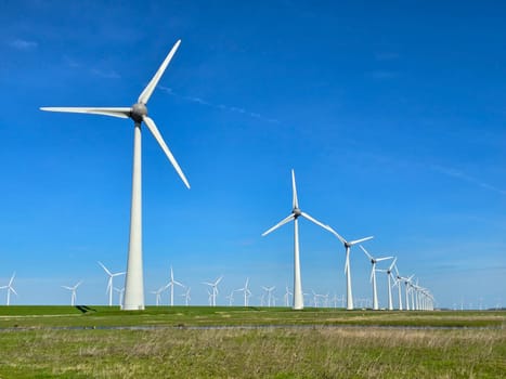 Windmill park in the meadow on a sunny day, view of windmill turbines on a Dutch dike generating green energy electrically, windmills isolated at sea in the Netherlands.