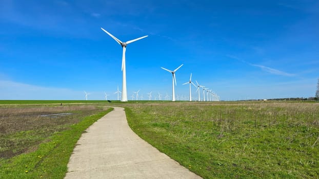 Windmill park in the meadow, view of windmill turbines on a Dutch dike generating green energy electrically, windmills isolated at sea in the Netherlands.