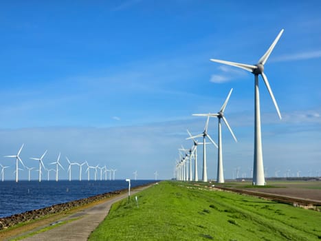 windmill turbines on a Dutch dike generating green energy electrically, windmills isolated at sea in the Netherlands. Energy transition, zero emissions, carbon neutral, Earth day concept