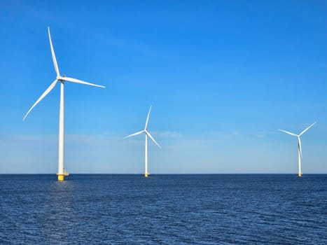 windmill turbines on a Dutch dike generating green energy electrically, windmills isolated at sea in the Netherlands. Energy transition, zero emissions, carbon neutral