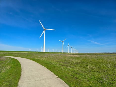 view of windmill turbines on a Dutch dike generating green energy electrically, windmills isolated at sea in the Netherlands.
