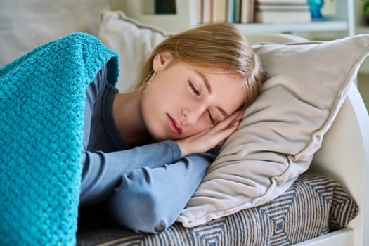 Sleeping relaxed resting young teenage female, with her eyes closed, lying on pillow under blanket at home on couch. Health, rest calm peace, beauty, lifestyle, youth concept