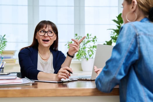 Female psychologist therapist working with young teen girl sitting in office. Teenage female student at therapy meeting with counselor. Psychology therapy psychotherapy youth mental health treatment