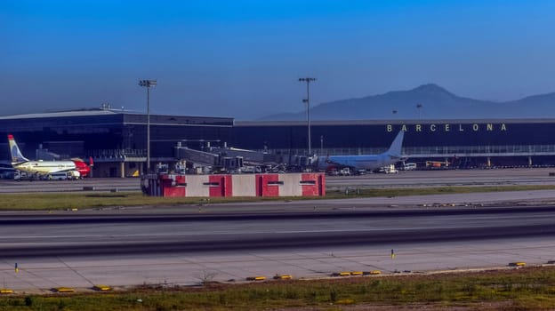 Barcelona airport with parked planes and mountains in the background with mountain view. High quality photo