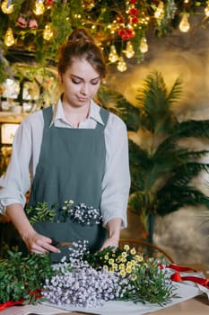 A woman in her florist shop collects bouquets of flowers. The concept of a small business. Bouquets of tulips for the holiday on March 8