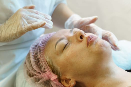 A woman lying down and receiving a facial massage from a therapist in a spa.