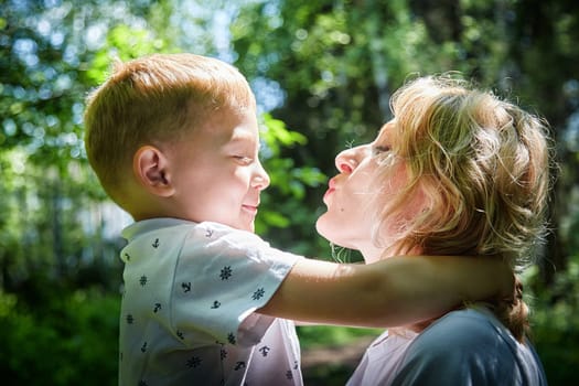 A mother and young son sharing a loving gaze among vibrant green trees