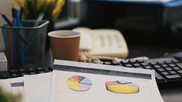 Audit report on desk next to paper cup of coffee in empty accounting department office, close up shot. Clipboard with papers containing economic graphs and figures near hot beverage on table