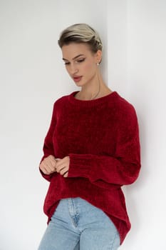 young beautiful woman posing in a red sweater in the studio