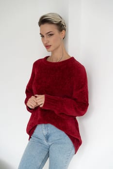 young beautiful woman posing in a red sweater in the studio