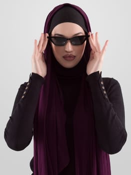 Portrait of beautiful stylish young muslim woman wearing black hijab and sunglasses as modern eastern fashion concept posing on white background. High quality photo