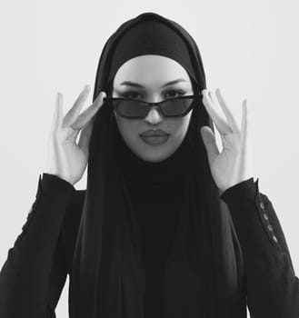 Portrait of beautiful stylish young muslim woman wearing black hijab and sunglasses as modern eastern fashion concept posing on white background. High quality photo