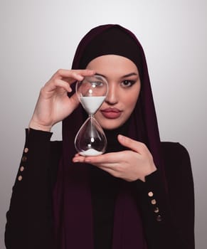 Beautiful arab businesswoman wearing hijab and holding sand clock. Time is passing and it's a pressure concept. High quality photo