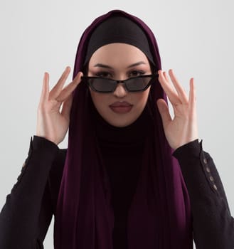 Portrait of beautiful stylish young muslim woman wearing black hijab and sunglasses as modern eastern fashion concept posing on white background. High quality photo