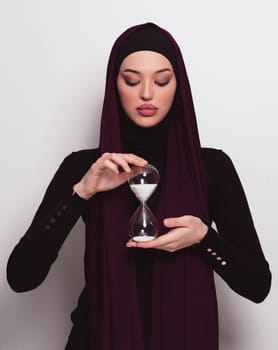 Beautiful arab businesswoman wearing hijab and holding sand clock. Time is passing and it's a pressure concept. High quality photo