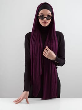 Portrait of beautiful stylish young muslim woman wearing black hijab and sunglasses as modern eastern fashion concept posing on white background. High quality photo