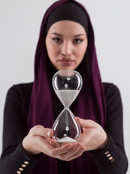 Beautiful arab businesswoman wearing hijab and holding sand clock. Time is passing and it's a pressure concept. High quality photo