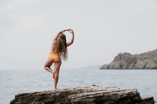 Woman meditating in yoga pose silhouette at the ocean, beach and rock mountains. Motivation and inspirational fit and exercising. Healthy lifestyle outdoors in nature, fitness concept.