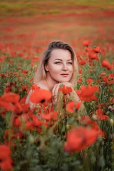 Happy woman in a red dress in a beautiful large poppy field. Blond sits in a red dress, posing on a large field of red poppies.