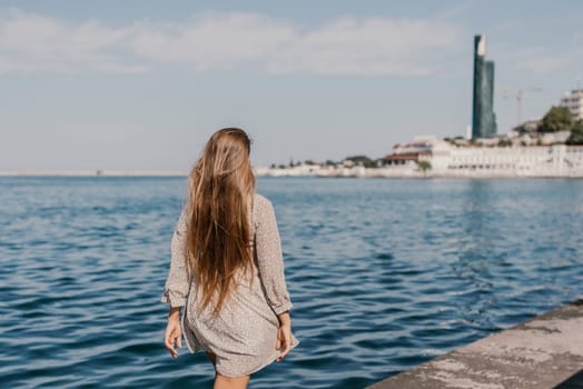 woman in a white dress is walking on a pier near the water. The scene is peaceful and serene, with the woman's long hair blowing in the wind