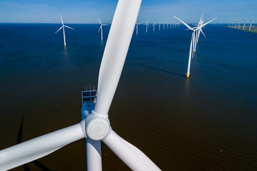 A group of wind turbines gracefully spinning in the ocean, harnessing the power of the wind in Flevoland, Netherlands during the vibrant season of Spring. Windmill turbines green energy in the ocean