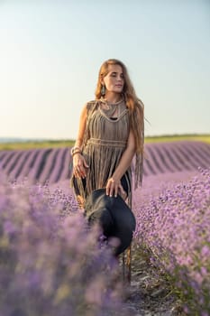 A woman is standing in a field of purple flowers, wearing a black dress and a black hat