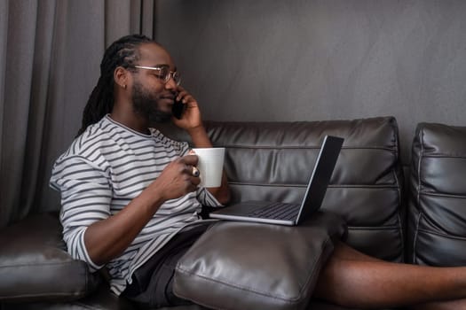 Young African American businessman spends his free time working from home on his laptop..