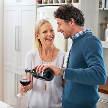 Couple, wine and drinking to celebrate love in home, marriage and relax on anniversary or date. People, glasses and alcohol for milestone in relationship, romance and care in connection or bonding.