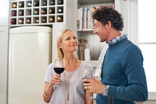 Couple, alcohol and drinking to celebrate love in home, marriage and relax on anniversary. People, glasses and red wine for milestone in relationship, romance and care in connection or bonding.