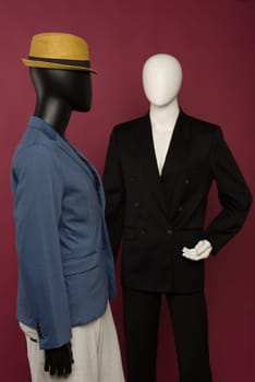 Two male mannequin in a black business suit and in a blue suit and white pants on a ruby background - image