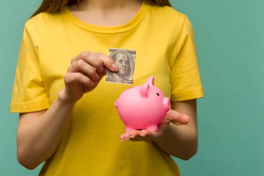 woman hand putting 100 dollars into piggy for saving money wealth and financial concept.- image