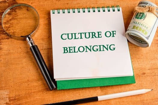 Culture of belonging symbol on a notebook with a magnifying glass and a roll of money on a papyrus background
