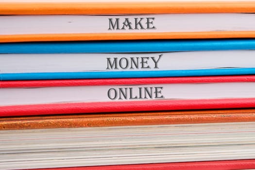 Business concept. MAKE MONEY ONLINE lettering written on notebooks stacked in a pile