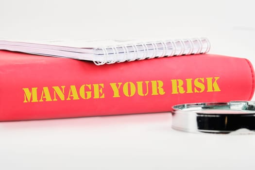 Business and manage your risk concept. Concept word Manage your risk on the back of the book cover, a notebook on a white background