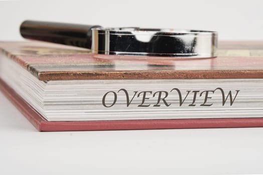 OVERVIEW written on a book with a magnifying glass on top on a white background