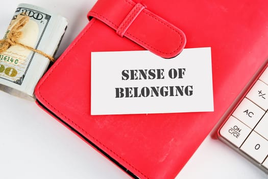 Business, sense of belonging concept. Text Sense of belonging on a business card on a business notebook near money and a calculator on a white background