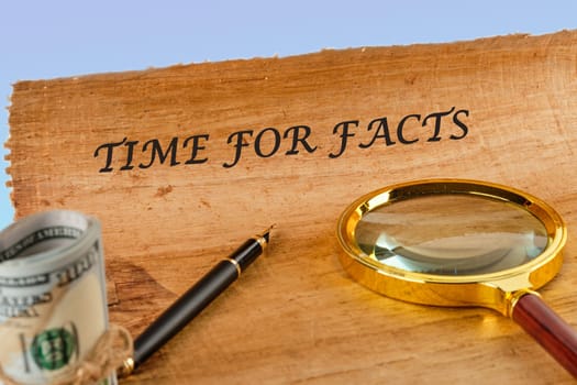 Time for facts message written on papyrus next to a magnifying glass and money