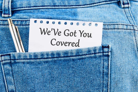 Text sign showing We Ve Got You Covered on a piece of paper that appeared from the pocket of jeans