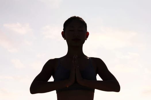backlight portrait of young woman practicing yoga in pray position, concept of mental relaxation and healthy lifestyle, copy space for text