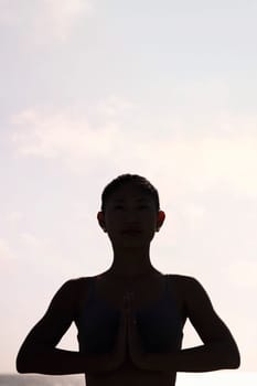 backlight portrait of young woman practicing yoga in pray position, concept of mental relaxation and healthy lifestyle, copy space for text