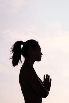 backlight portrait of young asian woman practicing yoga in pray position, concept of mental relaxation and healthy lifestyle, copy space for text