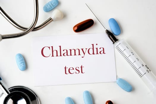 Medical concept. Chlamydia Test text on the card near the stethoscope, pills, syringe on a white background