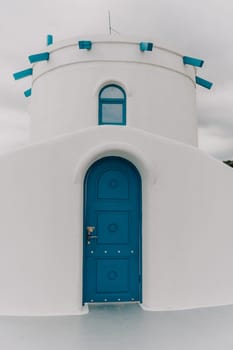 A blue door with a lock sits in front of a white building. The door is the only visible part of the building, and it is blue in color
