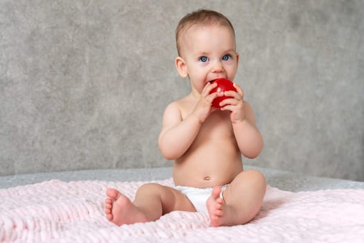 A kid with cheerful eyes is licking a small toy red ball with concentration.