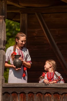 mother and daughter dressed in Ukrainian national costumes look at the camera