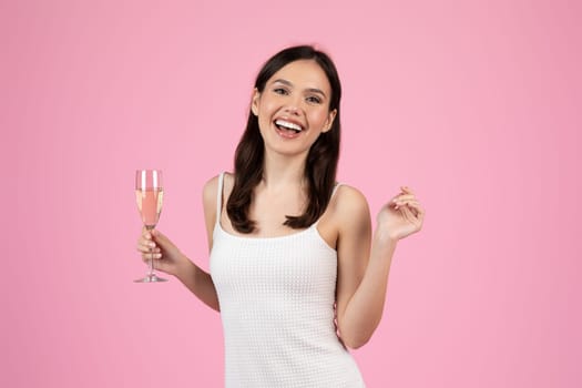 An exuberant lady holding a flute of champagne, embodying the spirit of celebration and summer, ideal for Generation Z imagery, isolated on pink