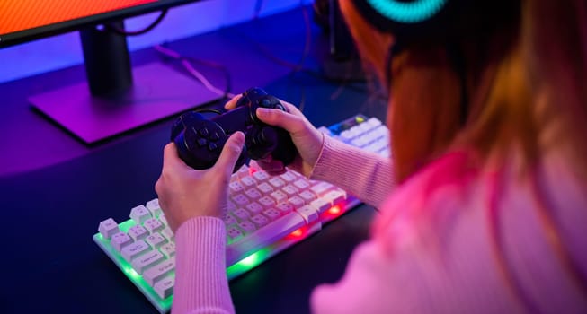 Close up Woman wear gaming headphones playing live stream esports games console at home, Gamer using joystick controller for virtual tournament plays online video game with computer neon lights