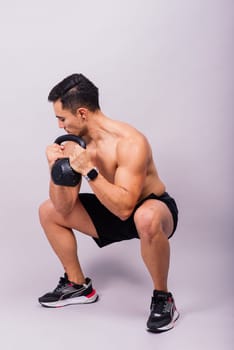 Strong young muscular focused fit man with a big muscles holding heavy kettlebells