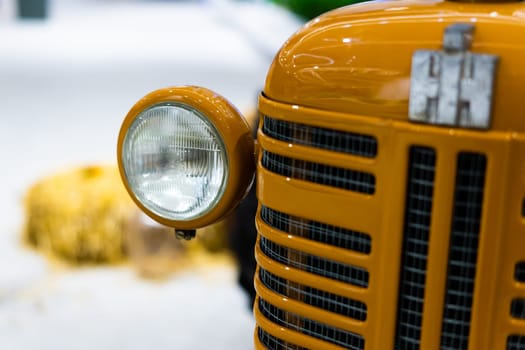 Small yellow tractor in an exhibition, closeup details, wheels